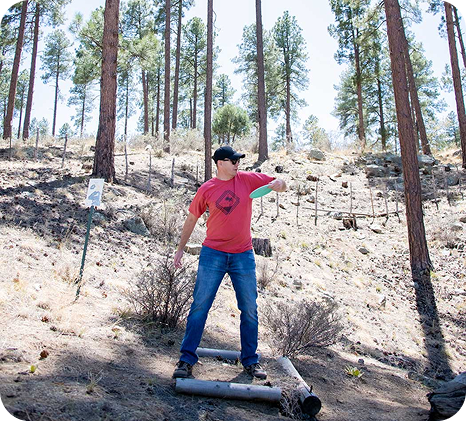 a man throwing a frisbee in the woods