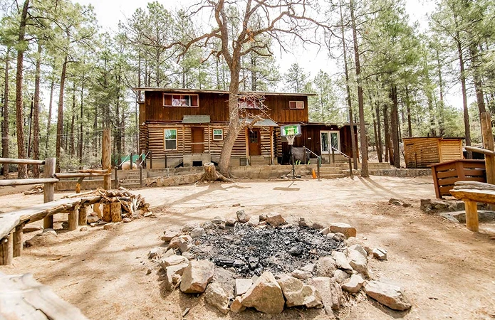 a log cabin with a fire pit in the middle of the yard