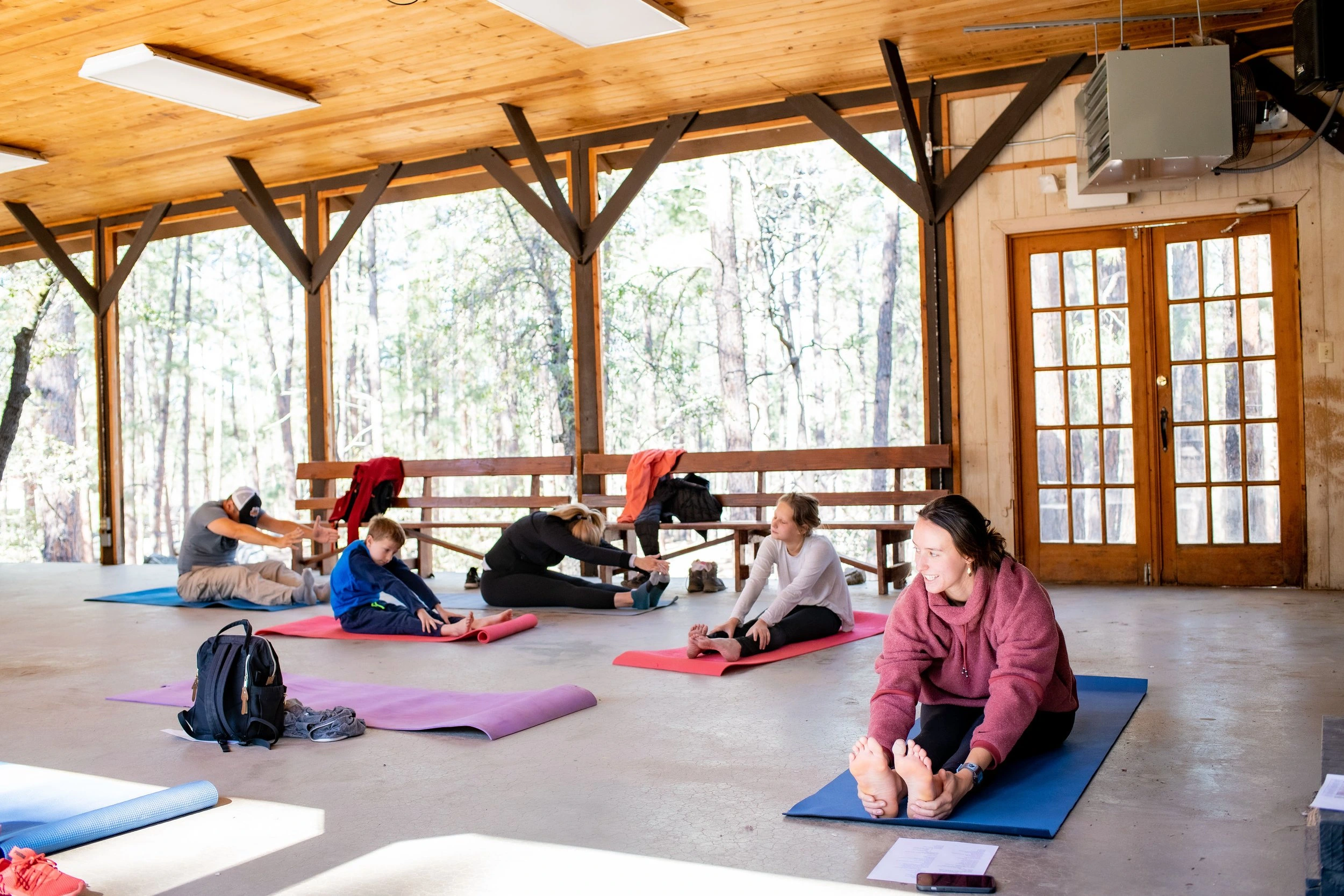 a group of people sitting on mats in a room with windows