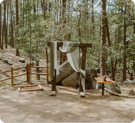 a wooden structure with a white cloth and a table in the woods