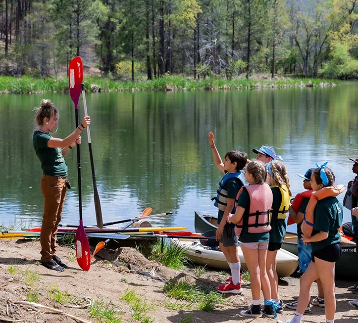 a group of people standing next to a woman holding a paddle