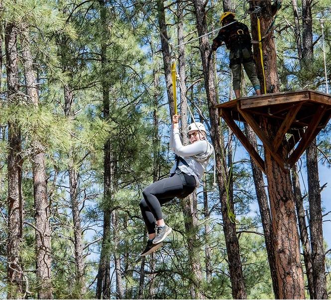 a woman in a white helmet from a rope in a tree