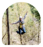 a woman in a helmet jumping from a tree